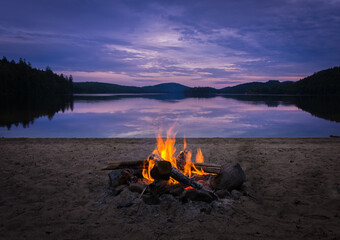 Burning campfire on the beach on my kayak camping trip - obrazy, fototapety, plakaty
