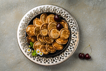 A trendy homemade breakfast with mini pancakes and cherries on the table in an openwork plate. Horizontal orientation