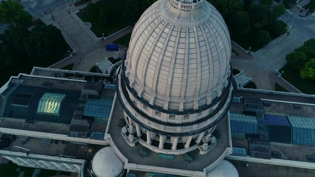 Low aerial drone shot of Wisconsin Capitol Dome during blue hour. The camera tilts down as it passes over the statue at the top of the dome.