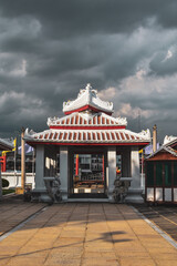 Entrada hacia el templo Wat Arun desde el río, color roja y blanco contra un cielo lleno de nubes