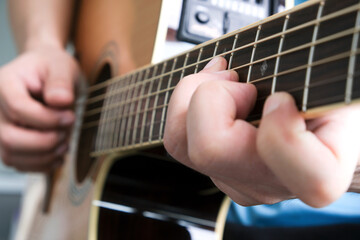 Fototapeta premium A man plays acoustic guitar at a resting room in his house.