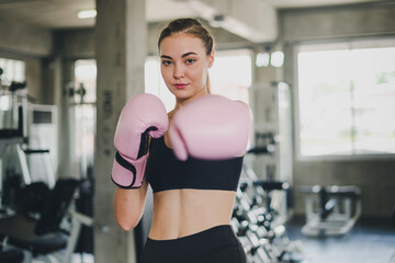 Beautiful girls exercise by boxing in the gym. She wears a pink boxing glove and wears exercise.