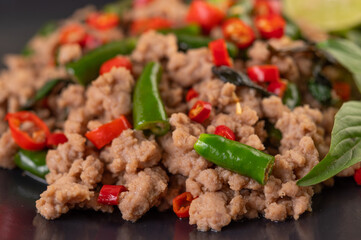 Stir-fried pork basil on banana leaves in a black dish.