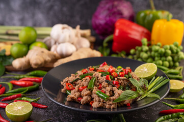 Stir-fried pork basil on banana leaves in a black dish.