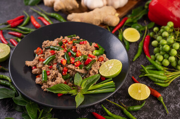 Stir-fried pork basil on banana leaves in a black dish.