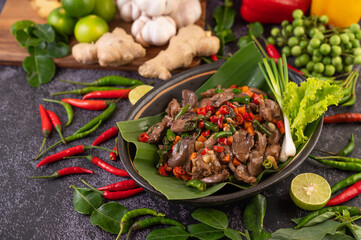 Stir-fried chicken liver basil on banana leaves in a black dish