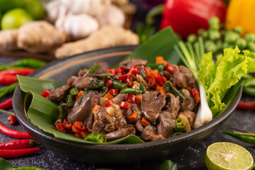 Stir-fried chicken liver basil on banana leaves in a black dish