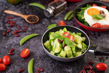 Cucumber stir-fried with tomatoes and red beans in a frying pan.
