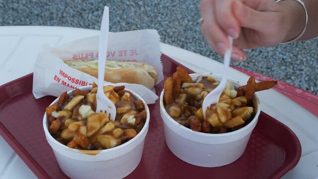 Woman eating traditional Quebec poutine with melting cheese curds