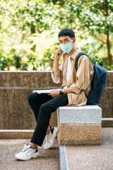 Obraz premium Men wearing masks sit reading books on the stairs.