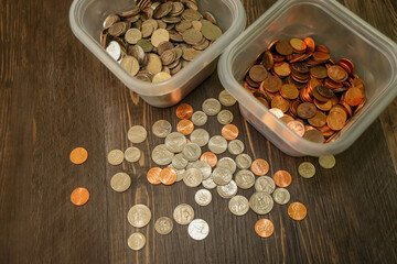 Two containers, one with junk silver and the other one with copper-plated zinc pennies. US coins scattered on wooden surface.