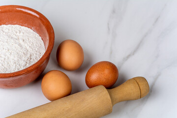 Rolling pin, cup of flour and eggs.