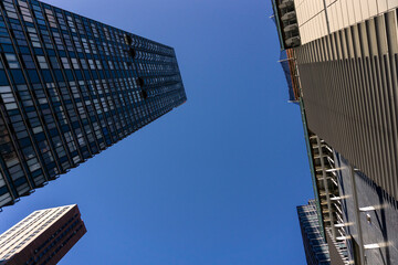 Fototapeta na wymiar Looking up a skyscrapers rising into the clear blue sky in New York City.