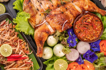 Grilled chicken on a plate with chili peppers, garlic sauce and sprinkled with pepper seeds.