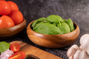 Thyme and tomatoes in a wooden cup with garlic on a wooden chopping board.