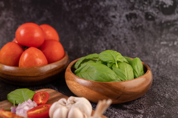 Thyme and tomatoes in a wooden cup with garlic on a wooden chopping board.