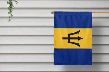 Barbados national small flag hangs from a picket fence along the wooden wall in a rural town. Independence day concept.