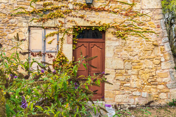 Fototapeta na wymiar Europe, France, Dordogne, Hautefort. Brown door in a stone house in the town of Hautefort.