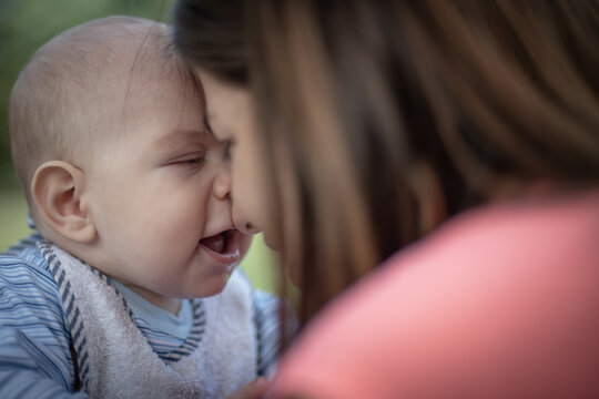 Beb&eacute; var&oacute;n con su mam&aacute; en un parque haciendo muecas mirando hacia la c&aacute;mara