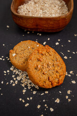 homemade cookies with oatmeal over black background with a light texture. 