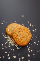 Vertical photo of homemade cookies with oatmeal over black background with a light texture. 