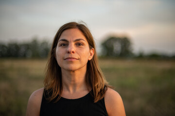 Mujer al atardecer o amanecer en campo de Argentina con árboles de fondo