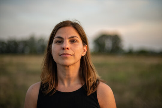 Mujer al atardecer o amanecer en campo de Argentina con &aacute;rboles de fondo