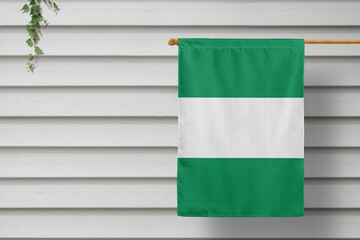 Nigeria national small flag hangs from a picket fence along the wooden wall in a rural town. Independence day concept.
