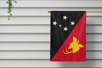 Papua New Guinea national small flag hangs from a picket fence along the wooden wall in a rural town. Independence day concept.