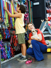 Woman with preteen boy choosing accessories for their havanese puppy in pet shop