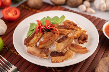 Pork belly fried on steamed rice on a plate.