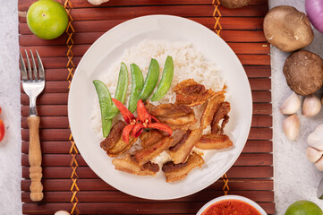 Pork belly fried on steamed rice on a plate.
