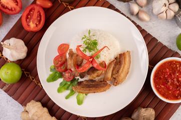 Pork belly fried on steamed rice on a plate.