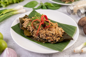 Mok bamboo shoots, put the pork on the banana leaf on a white plate.