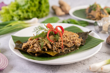 Mok bamboo shoots, put the pork on the banana leaf on a white plate.