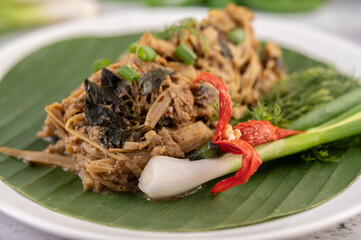 Mok bamboo shoots, put the pork on the banana leaf on a white plate.
