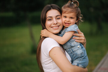 Portrait of beautiful mom with adorable little girl. Happy family outdoors. Daughter hug mum