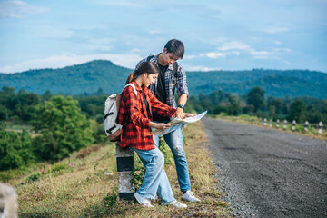 Male and female tourists standing look at the roadside map.