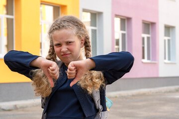Portrait of a schoolgirl on the background of the school. Concept  school days, Back to school. girl in a  uniform with a backpack. pupil, learner, scholar.