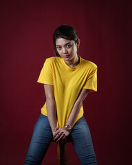 Front view yellow t-shirt Closeup on female body, woman girl in empty yellow t-shirt isolated on red background. Design woman t-shirt template and mockup for print.