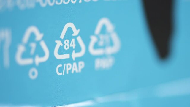 Macro view of recycling signs and other eco-labels on blue packaging background spbd. Figure helps to understand what kind of packages it is and whether it can be handed over for recycling. Letter