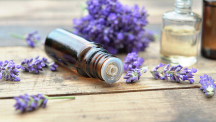 close on  bottle  of essential oil and bouquet of  lavender flower arranged on a wooden