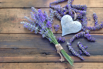 decorative metal heart among flowers of lavender on wooden background