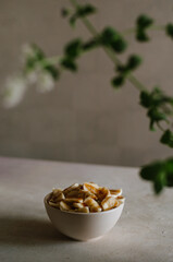 Pretty small ivory bowl with sliced banana on table in the kitchen with mint leaves decoration. Tasty and healthy vegetarian food isolated close up