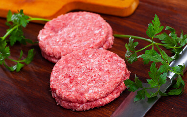 Raw meat cutlets for hamburgers on wooden surface