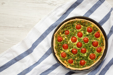 Homemade Spinach Quiche in a baking dish on a white wooden surface, top view. Flat lay, overhead, from above.