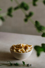 Pretty small ivory bowl with sliced banana on table in the kitchen with mint leaves decoration. Tasty and healthy vegetarian food 
