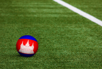 Cambodia flag on ball at soccer field background. National football theme on green grass. Sports competition concept.