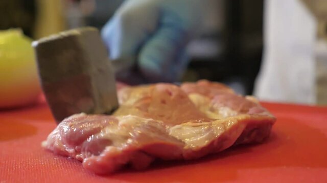 Slab of raw meat is beaten with a metallic tenderiser in a restaurant in slo-mo