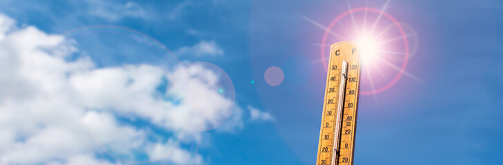 Thermometer against blue sunny sky. Hot summer weather concept.